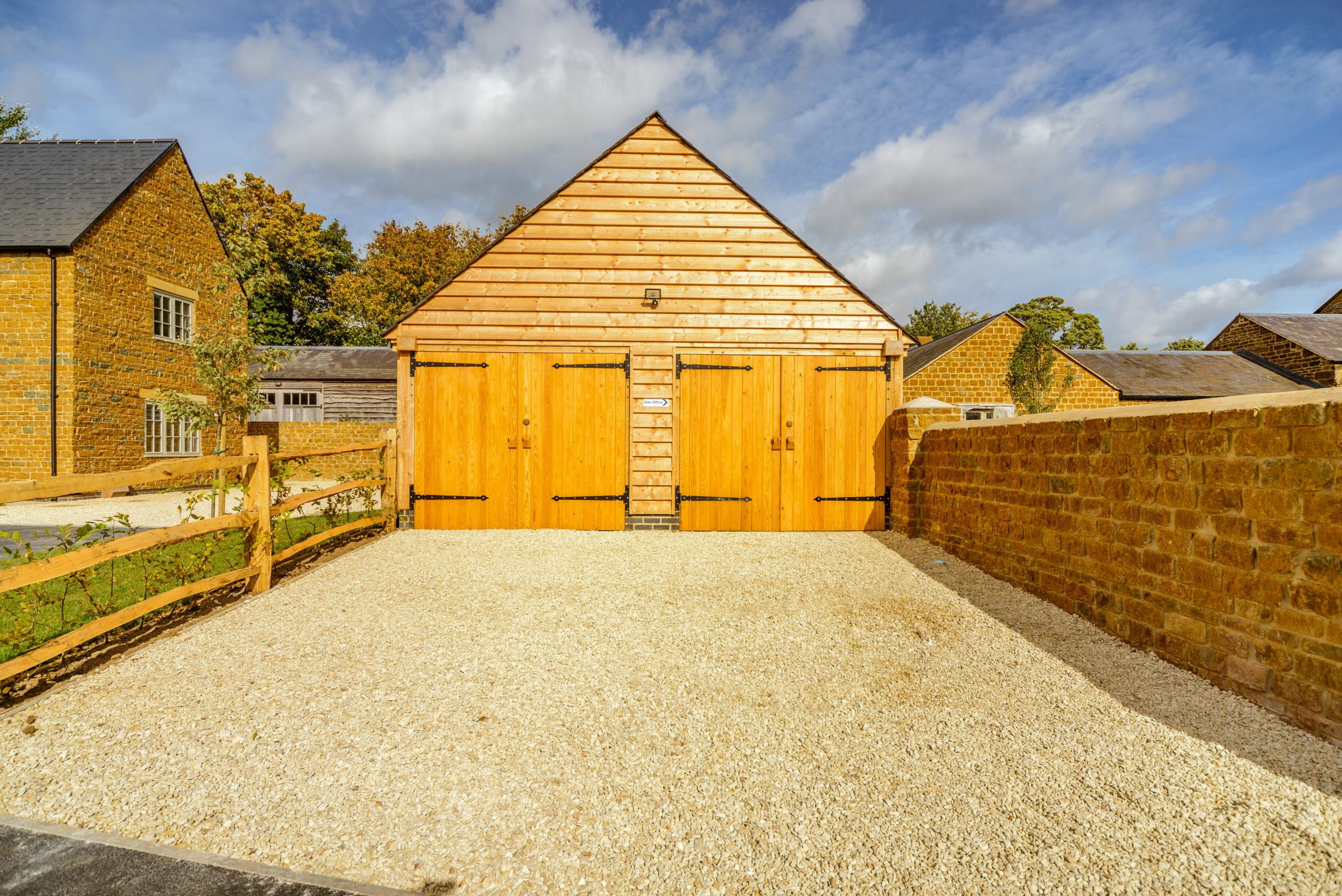 large 2 bay wooden oak garage with a gravel driveway in the foreground