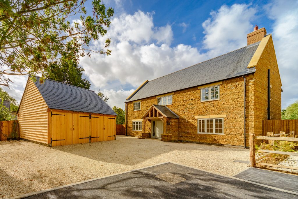 beautiful stone manor farm house with an oak framed garage on the left